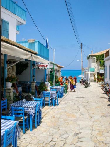 a street with blue tables and chairs and the ocean at Eolos Apartments with Private Parking in Agios Nikitas