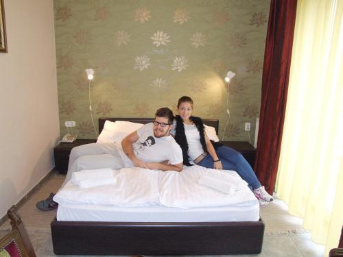 two men sitting on top of a bed at Thermal Panzió Sárvár in Sárvár