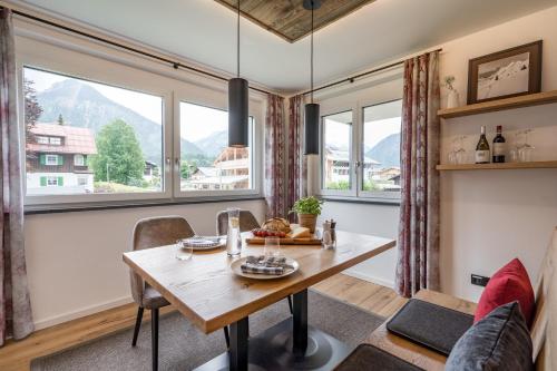 a dining room with a table and chairs and windows at Dorf Suites in Oberstdorf