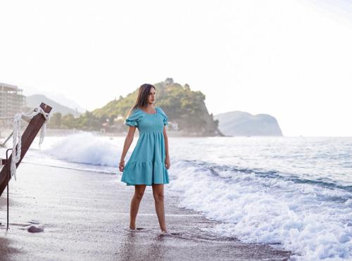 een vrouw in een blauwe jurk op het strand bij Hotel Riva by Aycon in Petrovac na Moru
