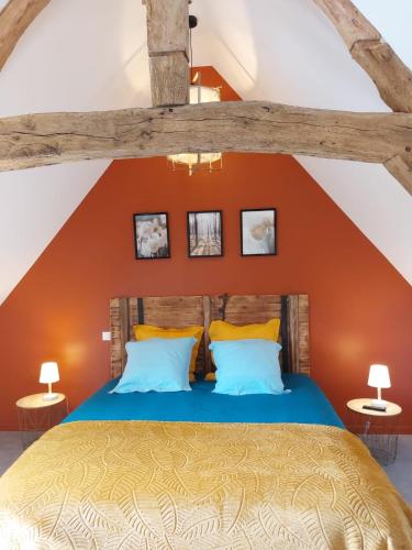 une chambre avec un lit avec un mur orange dans l'établissement Les Clématites, maison de campagne., à Boissy-lès-Perche