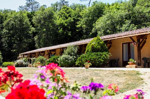 une maison avec des fleurs devant dans l'établissement Ferme Auberge Du Roc, à Les Vauries