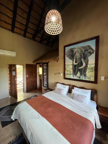 Crocodile Kruger Safari Lodge في مارلوث بارك: غرفة نوم بسرير كبير فيها صورة لفيل