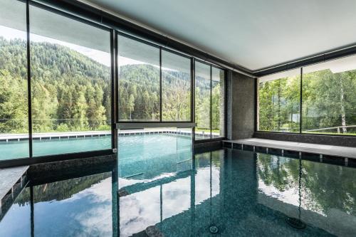 a house with a swimming pool with windows at Gaia Residence Hotel in Mezzana