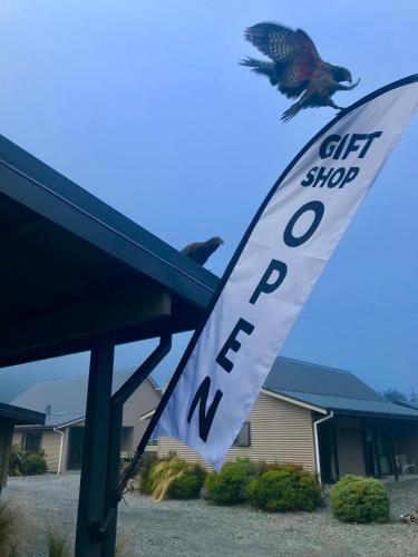 a bird flying over a gift shop sign with a flag at Arthur's Pass Motel & Lodge in Arthur's Pass