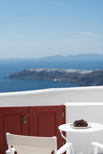 a white table and chairs and a table and a table at Serendipity Cliffside Villa & Suites in Imerovigli