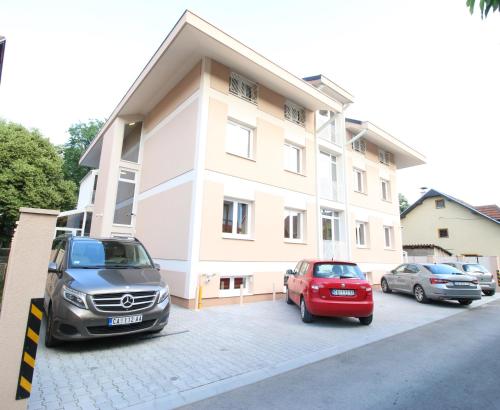 dos autos estacionados en un estacionamiento frente a un edificio en Grand Park rooms & apartments en Čačak