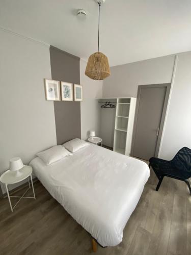 a bedroom with a large white bed and a chair at Le Relais de la Gare in Dole