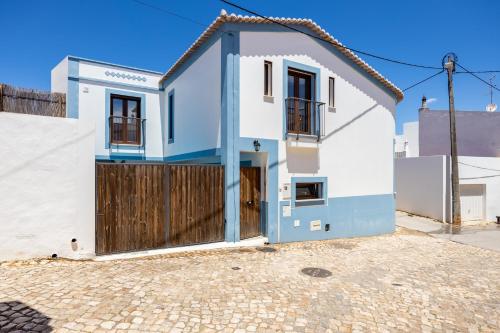 a white and blue house with a wooden gate at Casa da Vuvu Montes de Alvor in Alvor
