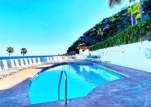 ein Pool neben einem Strand und dem Meer in der Unterkunft Modern Hamilton Cove Villa w/golf cart in Avalon