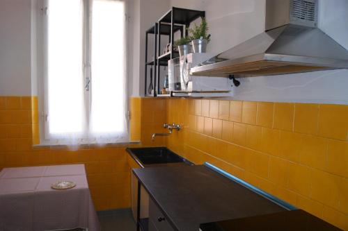 a kitchen with yellow tiles on the wall and a sink at Castiglioncello Blue Nest in Rosignano Solvay