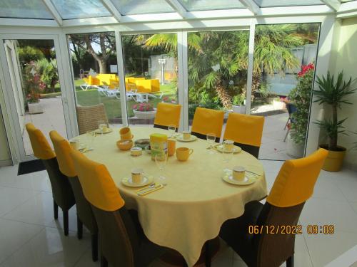 a dining room with a table and yellow chairs at Locatlantique in Aytré