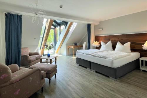 a bedroom with a bed and a chair and a couch at Hotel Wasserschloss Mellenthin in Mellenthin