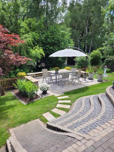 a patio with a table and an umbrella in a yard at Ferienwohnung Karin Vogel in Hilchenbach