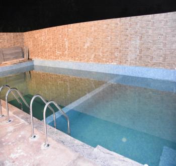 a swimming pool with a bench next to a building at ECR River Valley in Kodūr