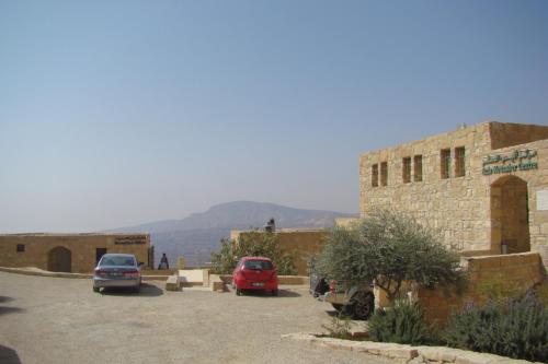 a parking lot with cars parked in front of a building at Dana Guesthouse in Dana