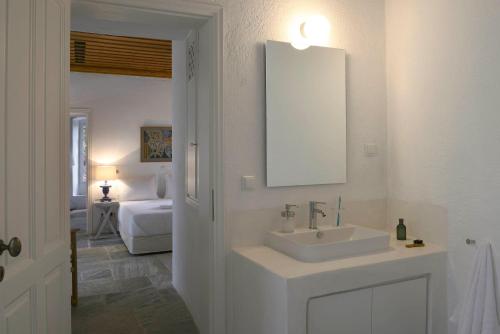 ein weißes Badezimmer mit einem Waschbecken und einem Spiegel in der Unterkunft Patrick & Joan Leigh Fermor House in Kardhamili