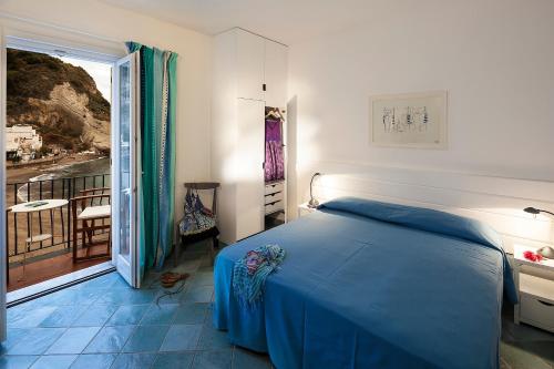 una camera con letto blu e balcone di Appartamenti Le Pleiadi - Sant'Angelo D'Ischia a Ischia