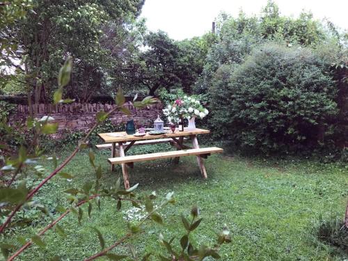a picnic table with flowers on it in a garden at Hornes Cottage in Longborough