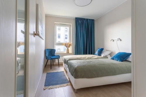 a bedroom with two beds and a blue chair at Betty by Q4Apartments in Gdańsk