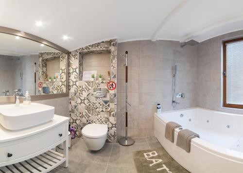 a bathroom with a tub and a toilet and a sink at Sunny House Izgrev in Balchik