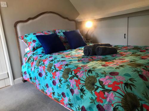 a bedroom with a bed with a floral bedspread at Hornes Cottage in Longborough