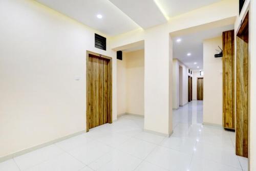 einen Flur mit weißen Wänden und Holztüren in der Unterkunft Hotel Blue Leaf in Rajkot