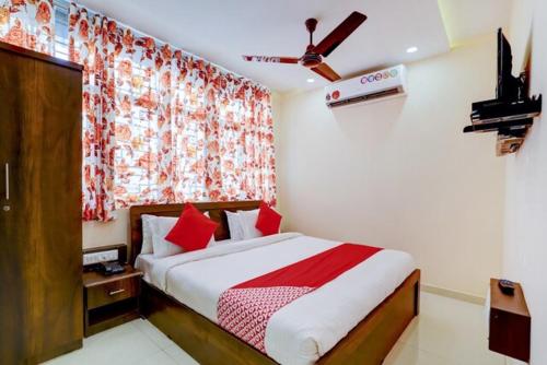 Schlafzimmer mit einem Bett mit roten Kissen und einem Fenster in der Unterkunft Hotel Blue Leaf in Rajkot