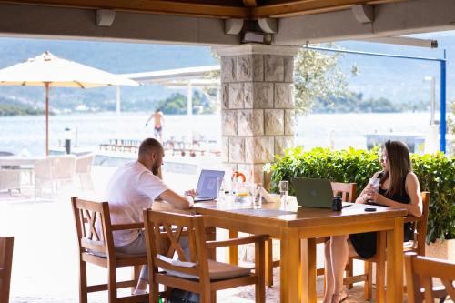 un hombre y una mujer sentados en una mesa con portátiles en Apart-hotel Villa Lav en Tivat