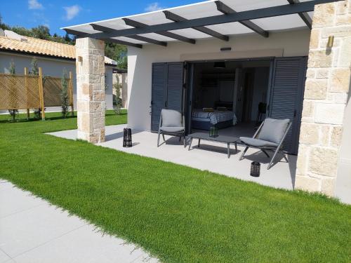 a patio with two chairs under a pergola at Alekos Beach Houses-Elia Villas in Lixouri