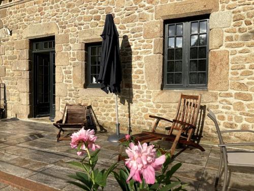 a patio with two chairs and an umbrella and flowers at La Forge De La Coudraie in Pleugueneuc