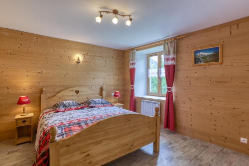een houten slaapkamer met een bed en een raam bij Le Chasseforêt in Termignon
