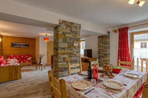 une salle à manger avec une table et un pilier en pierre dans l'établissement Le Chasseforêt, à Termignon