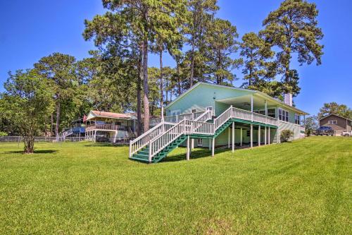 a green house with a staircase on a lawn at Waterfront Onalaska Retreat with Private Dock! in Blanchard