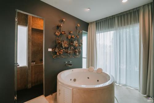 baño con bañera grande y ventana en Ohana Resort and Restaurant en Rayong