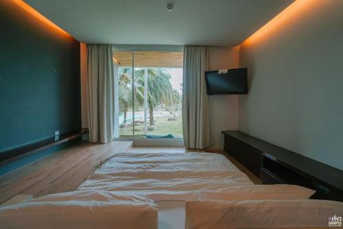 um quarto com uma cama e uma grande janela em Ohana Resort and Restaurant em Rayong