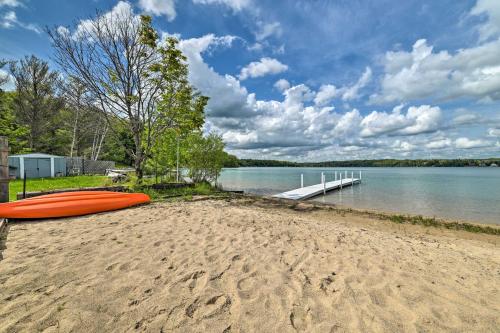 an orange kayak sitting on a beach next to the water at Northern Nights Beachfront Cottage in Kalkaska in Kalkaska