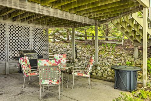a patio with a table and chairs and a stone wall at Waterfront Glenn Lake Condo Gas Grill and Views in Glen Arbor
