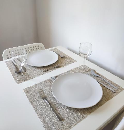 a table with white plates and silverware on it at Uroczy Apartament Pod Skarpą in Wadowice