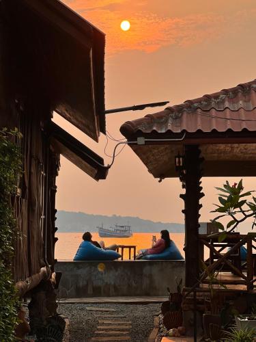 two people sitting on a balcony watching the sunset at Homebeach Resort เกาะล้าน in Ko Larn