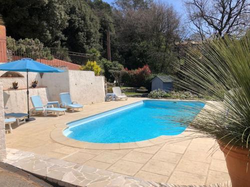 - une piscine dans une cour avec des chaises et un parasol dans l'établissement Studio indépendant de 32 m² dans les oliviers, à Belgentier