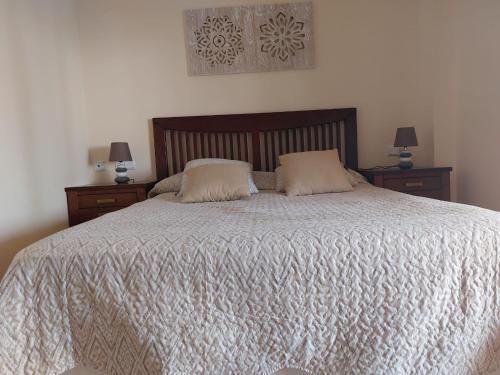 アヤモンテにあるApartamento Marina Esuriのベッドルーム1室(大型ベッド1台、ナイトスタンド2台付)