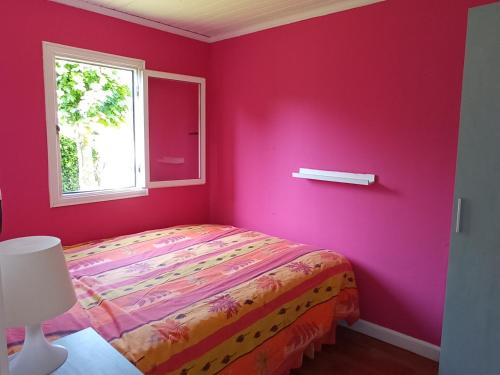 a pink bedroom with a bed and a window at Bonito bungalow con jardín en playa Nerga in Hio