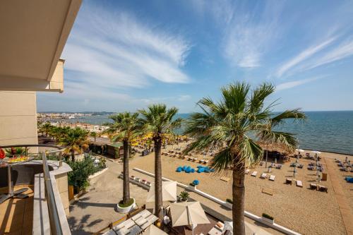 a view of a beach with palm trees and chairs at Hotel Zen in Durrës
