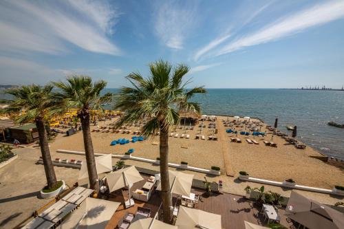 a beach with palm trees and chairs and the ocean at Hotel Zen in Durrës