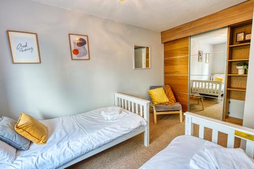 a bedroom with two twin beds and a chair at Cosy 3 bed apartment in Southam, sleeps 6 in Southam