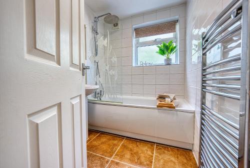 a bathroom with a tub and a sink and a window at Cosy 3 bed apartment in Southam, sleeps 6 in Southam