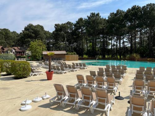 - un groupe de chaises assises à côté de la piscine dans l'établissement AGREABLE T2 LISIERE DU GOLF LACANAU OCEAN, à Lacanau-Océan