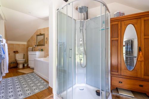 une salle de bain avec une douche avec une porte vitrée dans l'établissement Maison Bellini, à Plouër-sur-Rance