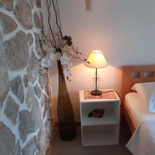 a table with a lamp and a vase with flowers at Apartment Vanda in Splitska